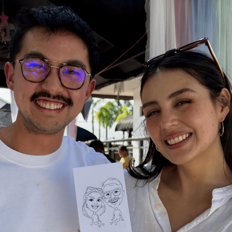 Couple sharing matching robot-drawn caricatures at a Robo-Draw party booth